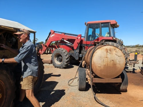 J1, j'aide Kevin, le grand père semi retraité, à creuser et enterrer un tuyau d'irrigation. Ça collecte par prendre le tracteur qui va creuser la digue, gonfler les pneus, faire le plein, fixer l'outilllage a l'arrière..